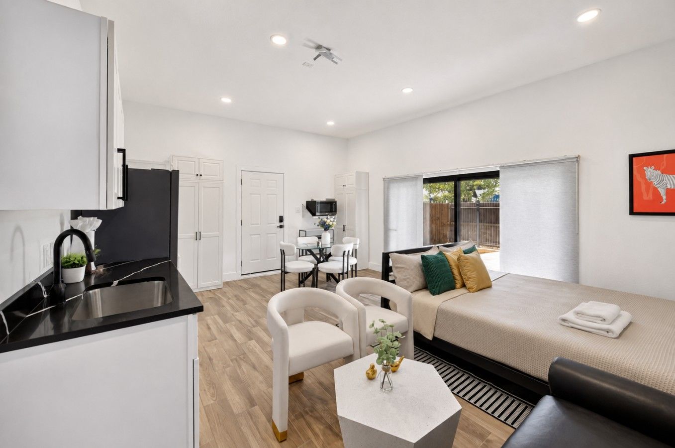A modern apartment with a kitchenette, a dining area, a living room with a sofa and a TV, and a large window.