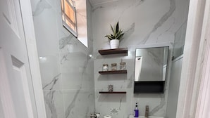 A compact bathroom with a toilet, sink, and shelves. - Belle Escape - Blue Room (Castries)