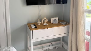A room with a flat-screen TV mounted on the wall, a wooden desk with a remote control, a Linksys Wi-Fi router, and a small white bowl. - Belle Escape - Blue Room (Castries)