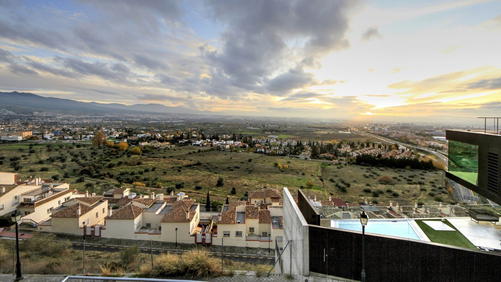 A residential area with houses, a road, and a distant cityscape.