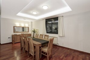 Ein Essbereich mit einem Holztisch und Stühlen, einem Spiegel über dem Tisch und einem Fenster mit Vorhängen.