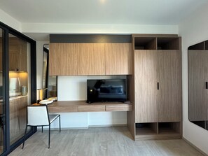 Een moderne woonruimte met een flatscreen televisie, houten kastwerk en een eethoek.