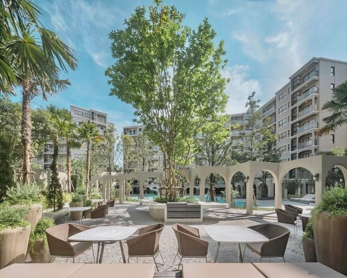 Zona de terrassa exterior amb zones d'estar, una piscina i vegetació al voltant.