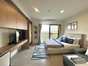 Ein modernes Hotelzimmer mit einem großen Bett, einem Fernseher, einem Balkon mit Blick und einem Schreibtisch.