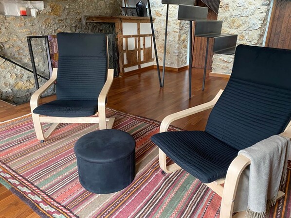 A room with two dark-colored chairs, a round ottoman, and a patterned rug.