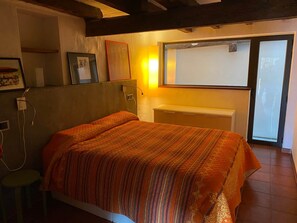 A bedroom with a bed, a wall-mounted lamp, and a window. - Stone Country House in La Tinença de Benifassà · Nature and a Fireplace (El Bellestar)