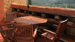 Een terras met een tafel, stoelen, een parasol en een stenen muur.
