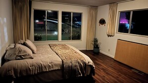 Un dormitorio con cama, cortinas, ventana, radiador y una planta.
