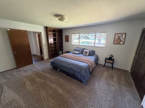 A bedroom with a bed, a nightstand, a window, and a built-in shelving unit.