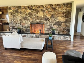 A living room with a stone wall, a fireplace, a sofa, and a coffee table.