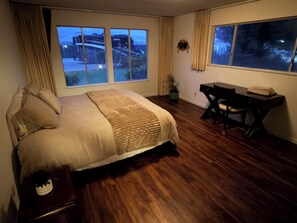 A bedroom with a large bed, a desk, and two windows offering a view of a road and a building. - Japanese garden estate in Monterey Count on a 40 acre ranch (Salinas)