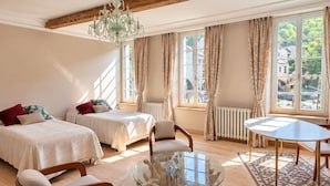 A room with two beds, a glass coffee table, and a dining table. - Maison Crone (Castillon-en-Couserans)