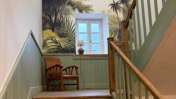 A staircase with wooden steps and a railing, leading to a room with a view of palm trees and a door.