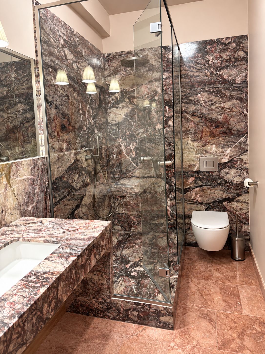 Une salle de bain moderne avec une douche à parois de verre, un lavabo en marbre et des toilettes.