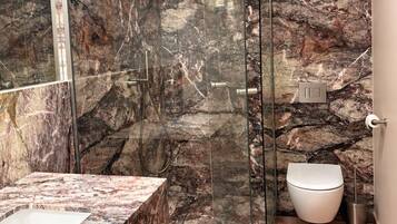 Une salle de bain moderne avec une douche à parois de verre, un lavabo en marbre et des toilettes.