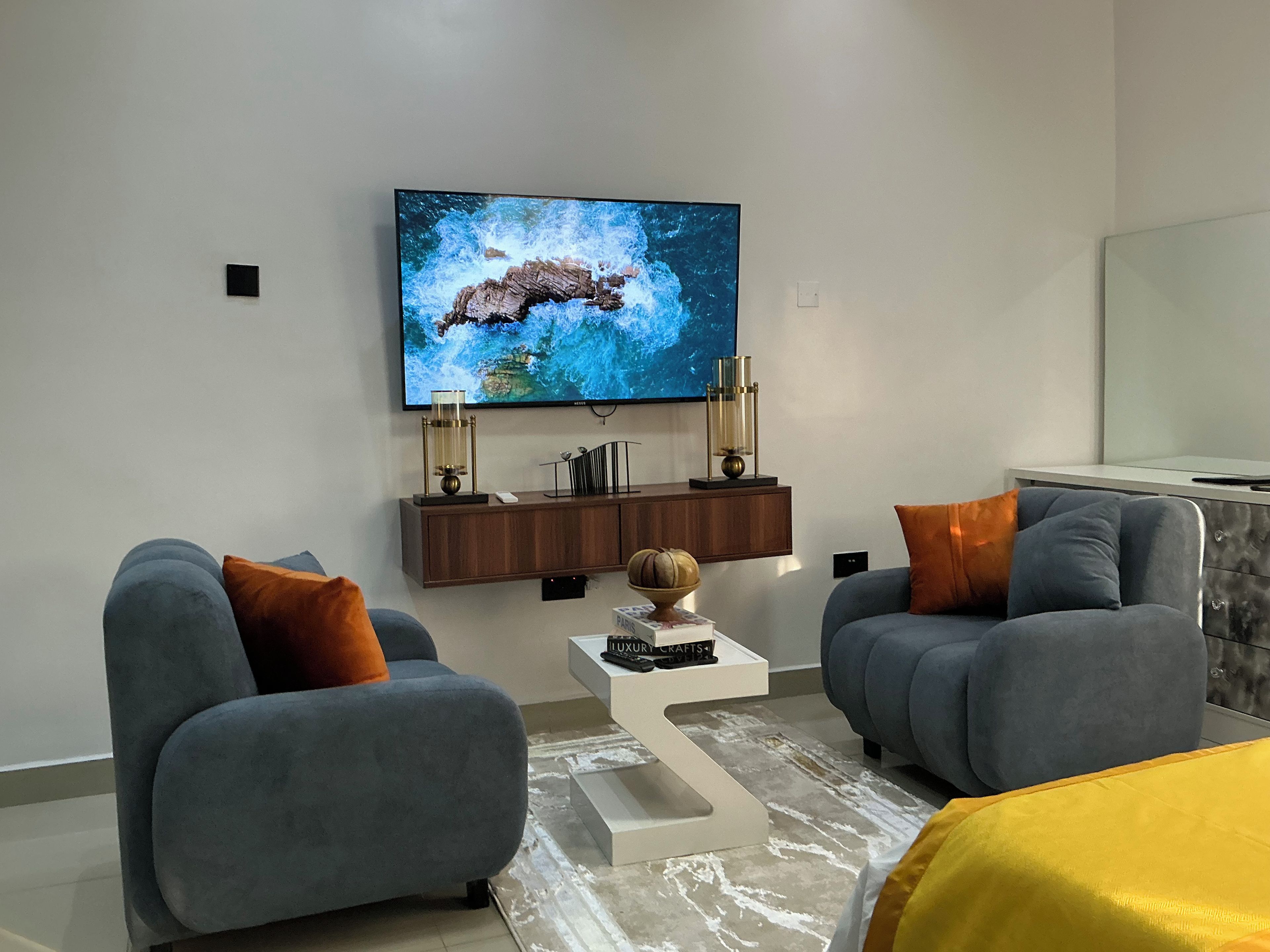 A modern living room with two sofas, a coffee table, and a flat-screen TV mounted on the wall.