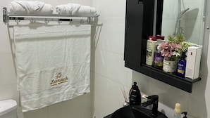 A bathroom with a white towel hanging on a rack, a black cabinet with toiletries, and a mirror above the sink. - Lexrach Luxury Apartments (Abuja)