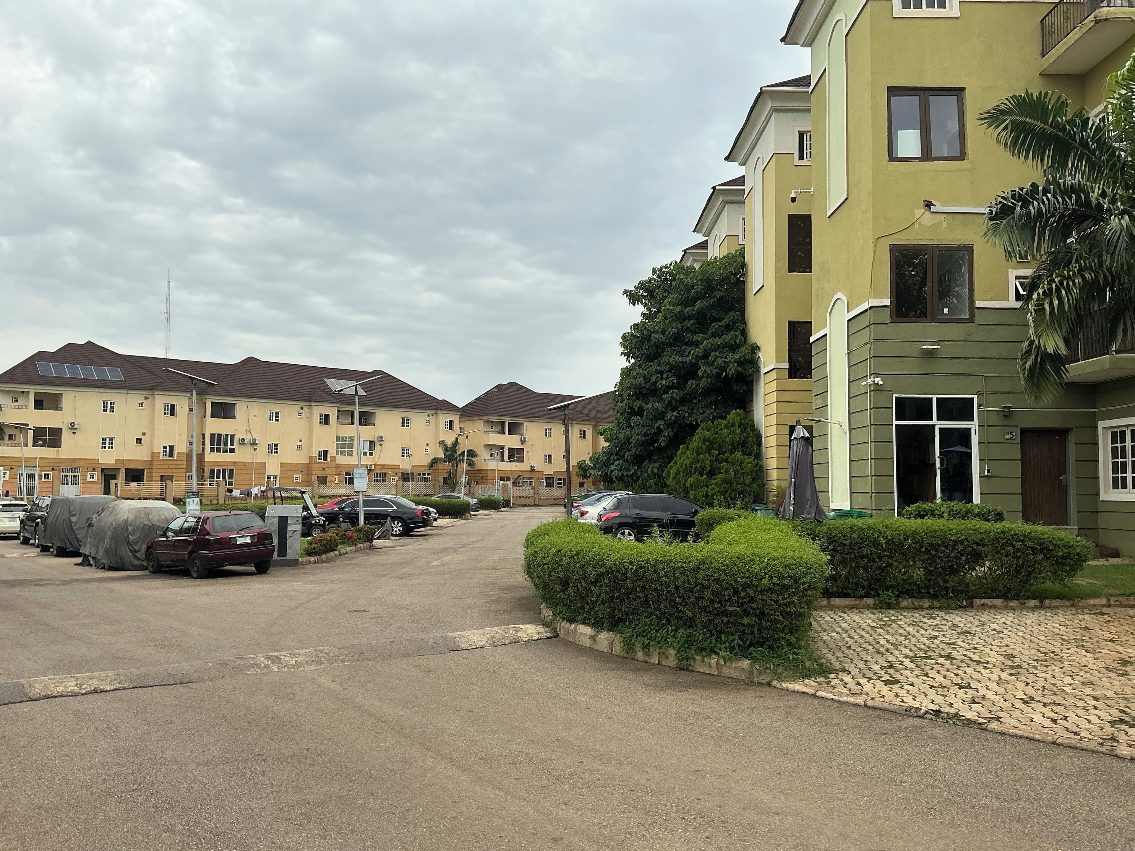 Quartiere residenziale con edifici a più piani, un parcheggio e un prato curato.