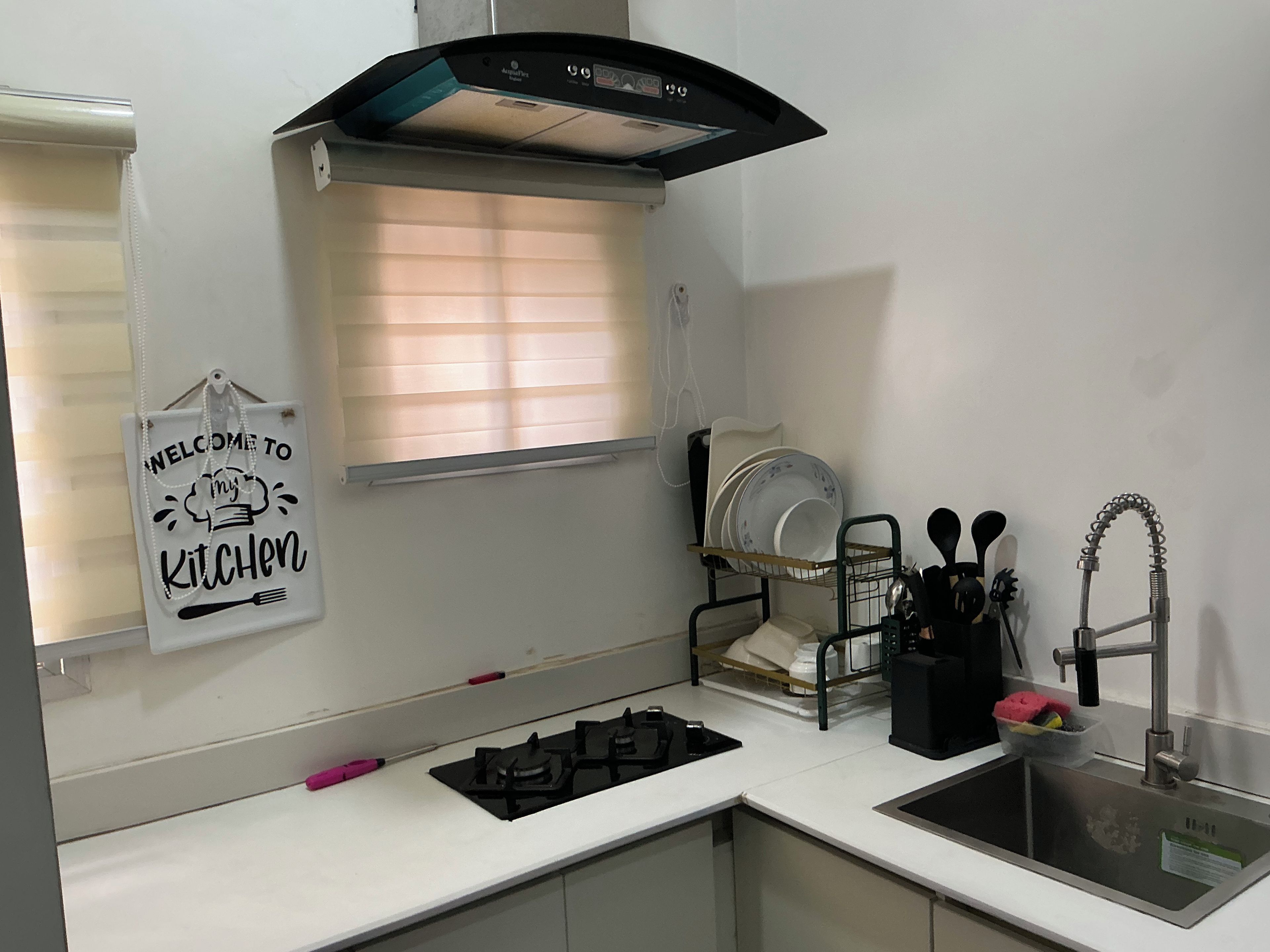Una cocina con estufa a gas, un fregadero, un escurreplatos y una ventana con persianas.