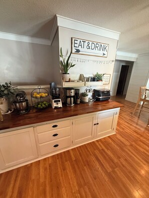 A kitchen with a wooden countertop, a sign reading 'EAT & DRINK', and various kitchen appliances.