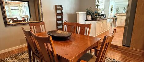 A dining area with a wooden table and chairs, a ceiling fan, and a patterned rug.