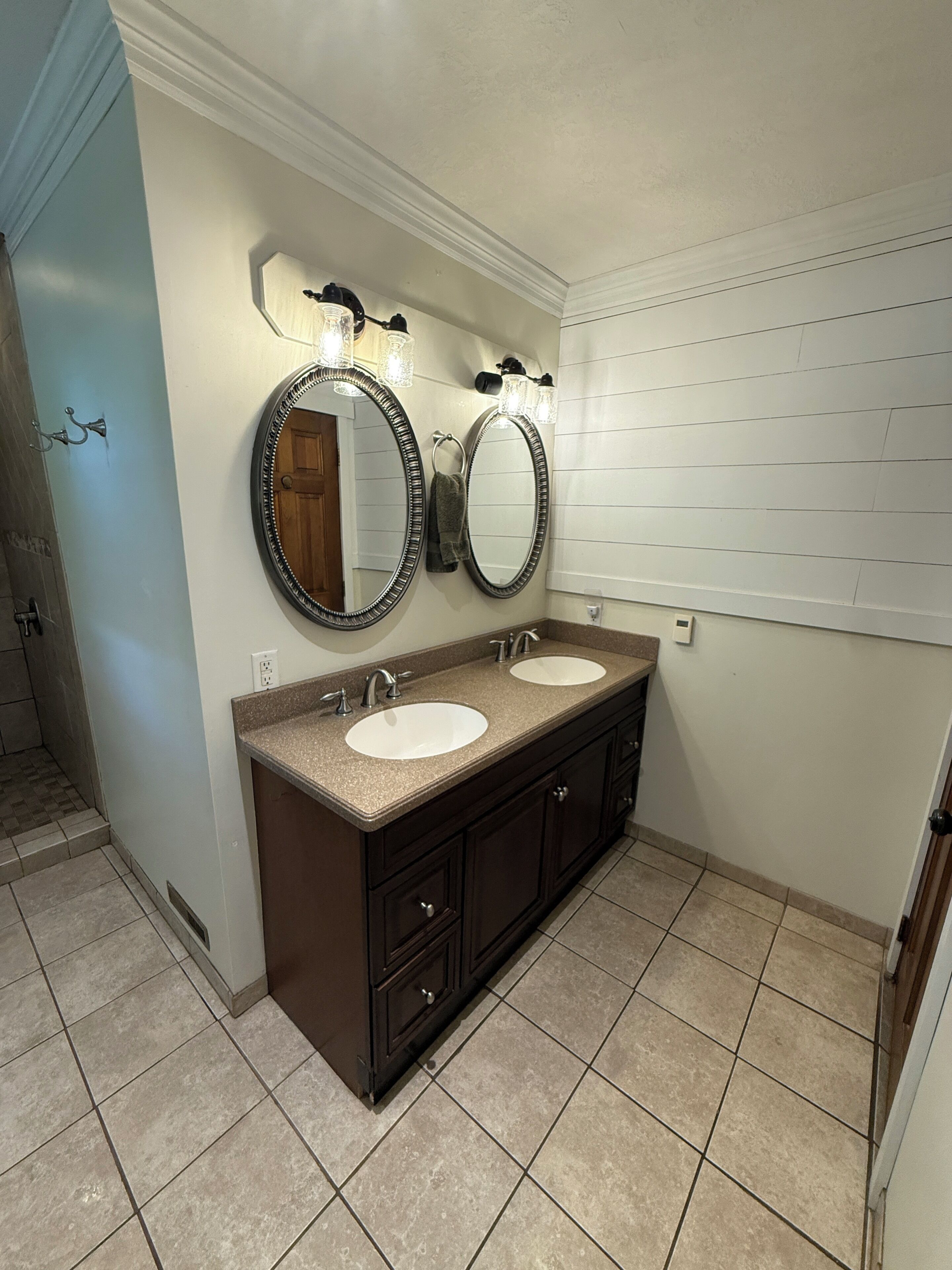 A bathroom with two sinks, a dark vanity, and a mirror with light fixtures.