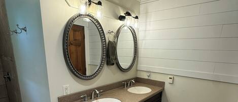 A bathroom with two sinks, a dark vanity, and a mirror with light fixtures.