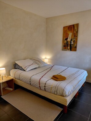 Ein Schlafzimmer mit Bett, Nachttisch, Lampe und einem Bild an der Wand.