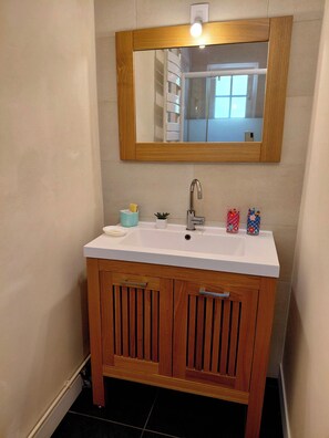 Ein Badezimmer mit einem weißen Waschbecken, einem Holzkästen und einem Spiegel darüber.