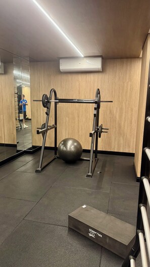 Ein Fitnessraum mit einem Squat-Stand, einem Medizinball und einem Spiegel.