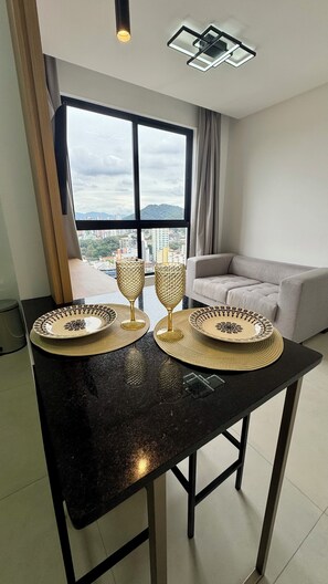 Un saló modern amb una finestra gran, un sofà i una taula de dinar amb plats decoratius i gots.