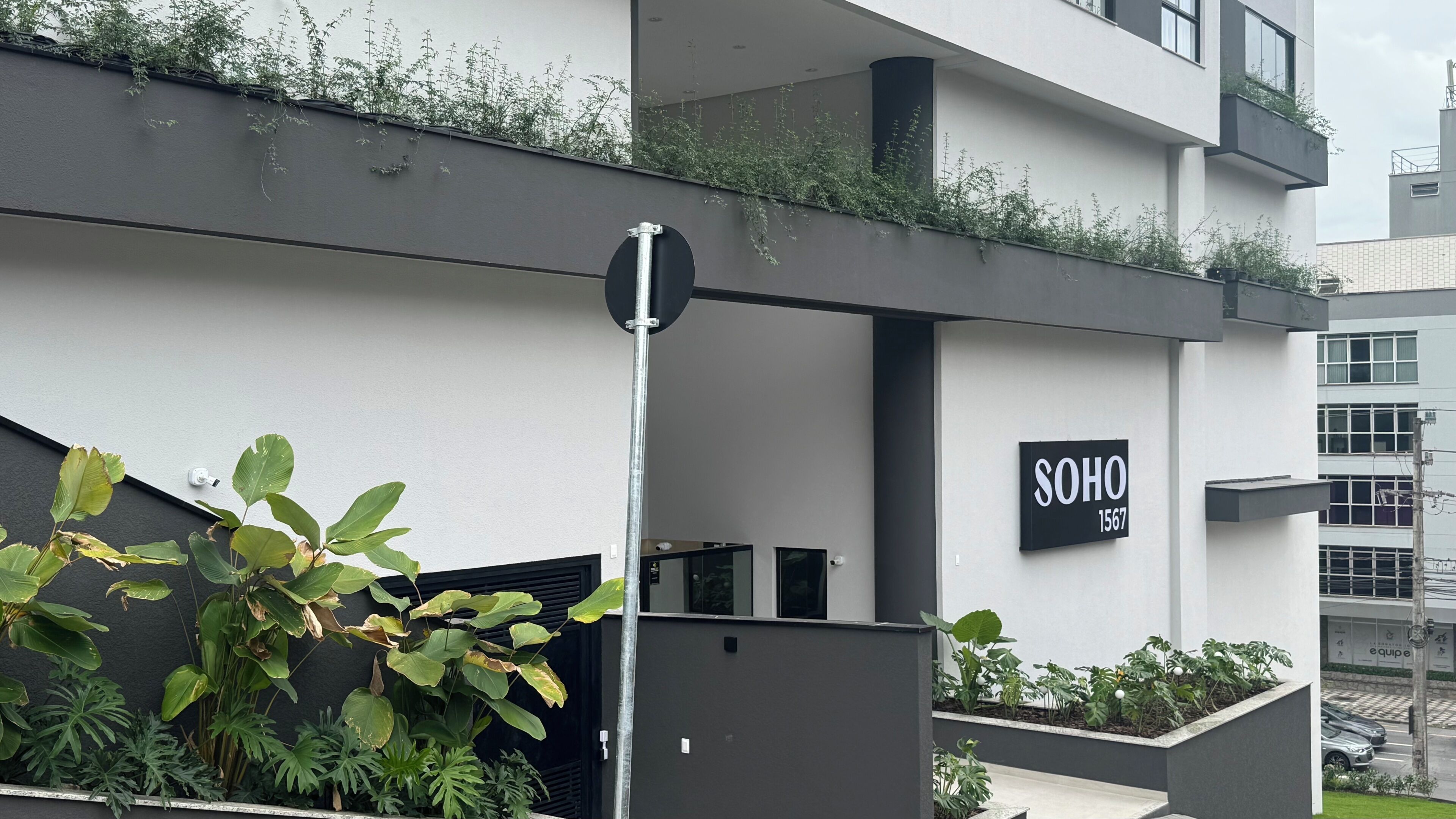 Un bâtiment moderne avec une enseigne indiquant « SOHO 1567 » et un poteau métallique.