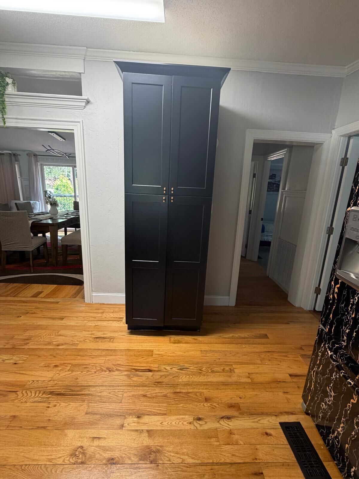 Een kamer met een donker houten garderobe, houten vloeren en een eethoek met een tafel en stoelen.
