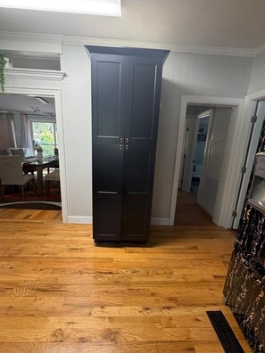 Ein Zimmer mit einem dunklen Holzschrank, Holzboden und einem Essbereich mit Tisch und Stühlen.