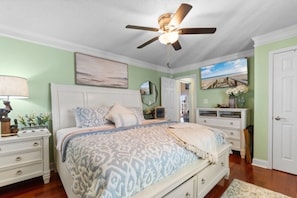 A bedroom with a bed, nightstands, a dresser, a ceiling fan, and a door. - The Gatsby House - Ocean View - Steps to Beach - 8BR 6BA (Murrells Inlet)