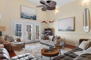 A living room with a sofa, armchairs, a coffee table, and a ceiling fan. - The Gatsby House - Ocean View - Steps to Beach - 8BR 6BA (Murrells Inlet)