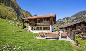 A modern chalet with a balcony, surrounded by a lush green lawn and a mountain backdrop. - MODERN CHALET RETREAT WITH ICONIC LAUTERBRUNNEN VIEWS (Lauterbrunnen)