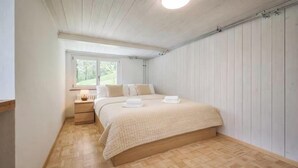 Une chambre à coucher avec un lit, une table de chevet et une fenêtre.