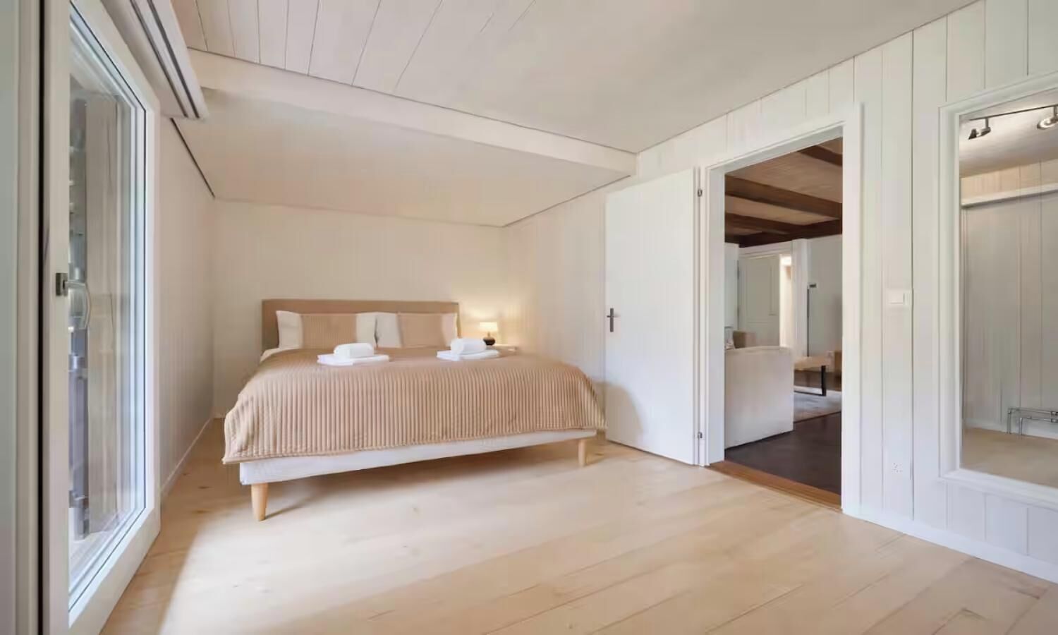 A bedroom with a bed, a bedside table, a nightstand, and a window.