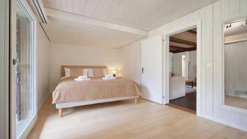 A bedroom with a bed, a bedside table, a nightstand, and a window.