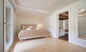 A bedroom with a bed, a bedside table, a nightstand, and a window.