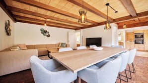 Un intérieur moderne avec un plafond en bois, une table à manger avec des chaises, un canapé et un téléviseur.