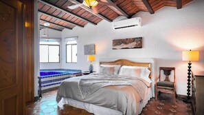 A bedroom with a bed, a nightstand, a lamp, a painting, and a window. - Panoramic Sea of Cortez Views at Casa Arco (San Carlos)