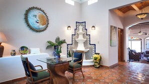 A spacious living area with a glass coffee table, wicker chairs, a decorative wall piece, and a tiled floor. - Panoramic Sea of Cortez Views at Casa Arco (San Carlos)