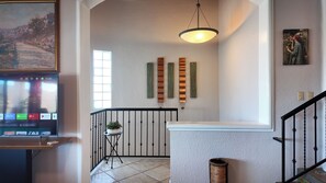 A staircase with a modern design, a television displaying a program, and a decorative wall with vertical elements. - Panoramic Sea of Cortez Views at Casa Arco (San Carlos)