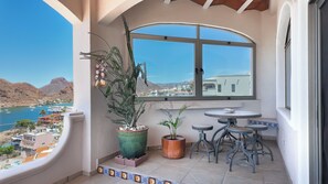 A balcony with a view of a coastal town, a potted plant, and a small table with chairs. - Panoramic Sea of Cortez Views at Casa Arco (San Carlos)