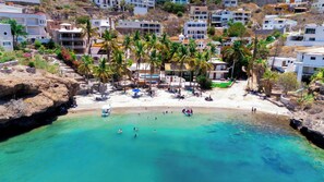 A coastal resort with a clear turquoise sea, palm trees, and white buildings. - Panoramic Sea of Cortez Views at Casa Arco (San Carlos)
