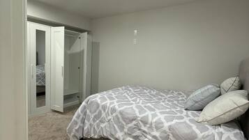 Une chambre à coucher comprenant un lit, une armoire et une porte donnant sur une autre pièce.