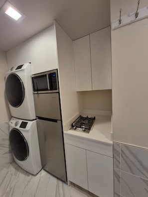 A compact kitchen with a built-in washer and dryer, a microwave, and a gas stove. - Modern 1BR Lake Washington Blvd Suite – Private, lake WA, parks & resturants (Kirkland)
