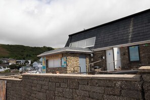 A building with a stone facade, a sign reading 'CAFE ON THE BEACH', and a small outdoor seating area. - Sandy Toes New 2026 Stylish 2Bed Steps from Beach (Challaborough)